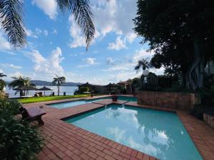 a swimming pool on a brick walkway next to the water at Olives by Agnes 31 in Hartbeespoort