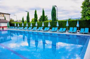 a large swimming pool with blue chairs and umbrellas at Elegance Spa Hotel in Ognyanovo