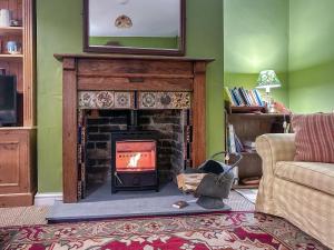 een woonkamer met een open haard en een tv erboven bij Stone Cottage - Swanage in Swanage
