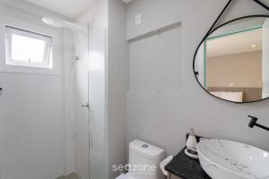 a white bathroom with a mirror and a sink at Sua estadia exclusiva em Blumenau a 350m da Vila Germânica - OCNs in Blumenau +15 photos