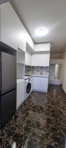 Tskhaltubo Spa Resort Apartments في Itʼkhvisi: مطبخ مع خزائن بيضاء وغسالة ومجفف