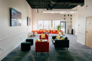 a room with couches and tables and orange chairs at The Citrus Hotel in Tavares