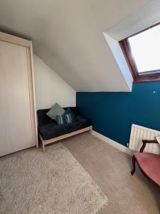 a attic room with a black couch with a window at Millers Barn in Farthinghoe