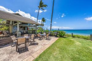 a patio with tables and chairs next to the ocean at Kahana Village 31 · KHV 31 Spacious Direct Oceanfront 3BD Condo in Kahana