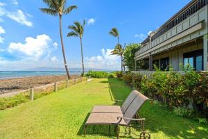 a bench sitting in the grass next to a building at Kahana Village 26 · KHV 26 2BD Direct Ocean Front with Amazing S in Kahana