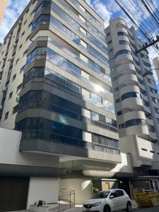 un coche aparcado delante de un edificio alto en Apartamento Meia Praia, en Itapema