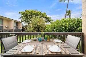 a wooden table with wine glasses on a deck at Kihei Garden Estates G207 · KGE G207 Newly Updated 2BD Condo AC in Kihei