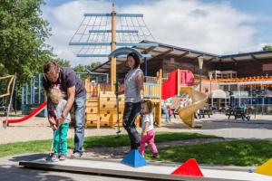 a man and two children playing in a playground at Vakantiepark Kijkduin - 870 in The Hague