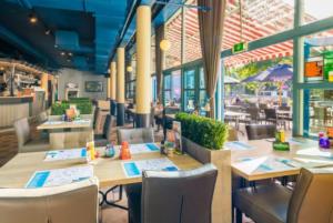 a restaurant with wooden tables and chairs and windows at Vakantiepark Kijkduin - 870 in The Hague