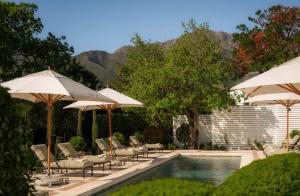 a swimming pool with umbrellas and chairs and a swimming pool at Maison Cabrière Boutique Hotel in Franschhoek +30 photos