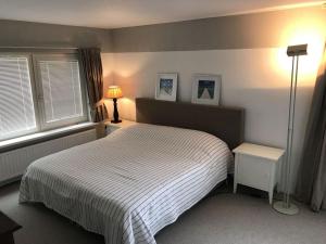 1 Schlafzimmer mit einem weißen Bett und 2 Fenstern in der Unterkunft Vrijvakantiehuis Rooistrand in Burgh Haamstede