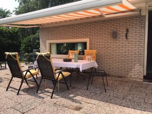 eine Terrasse mit Tisch und Stühlen und einer Backsteinmauer in der Unterkunft Vrijvakantiehuis Rooistrand in Burgh Haamstede