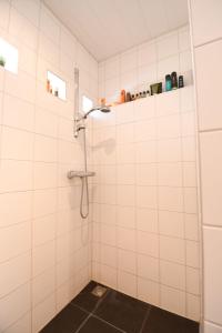 ein Badezimmer mit Dusche und weiß gefliesten Wänden in der Unterkunft Vrijvakantiehuis Rooistrand in Burgh Haamstede + 17 Fotos