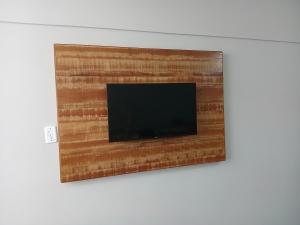 ein Flachbildfernseher, der an einer Wand hängt in der Unterkunft Studio 4 Boqueirão - Coração da Praia Grande in Praia Grande