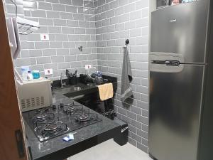 eine Küche mit einem Herd und einem Kühlschrank aus Edelstahl in der Unterkunft Studio 4 Boqueirão - Coração da Praia Grande in Praia Grande