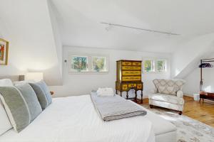 a white bedroom with a bed and a chair at Walker Cottage in Rockport