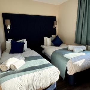 two beds in a hotel room with blue curtains at Sea Marge Seaview Lodges in Overstrand +6 photos