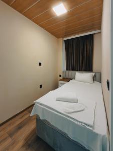 - une chambre avec un lit blanc et un plafond en bois dans l'établissement Onze Boutique Hotel Baku, à Baku