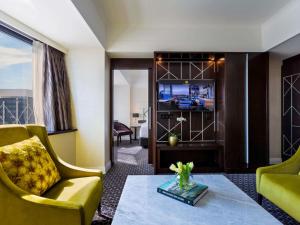a living room with a couch and a tv at Mövenpick Hotel Auckland in Auckland