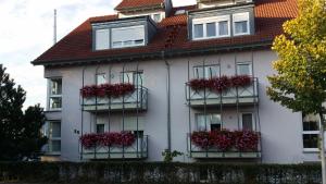 a white house with red flowers on balconies at Weingut Landmann Ferienwohnungen in Freiburg im Breisgau