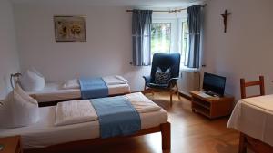 a room with two beds and a chair and a television at Weingut Landmann Ferienwohnungen in Freiburg im Breisgau