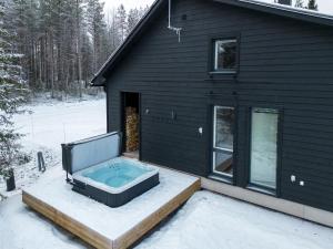 a hot tub sitting outside of a house in the snow at Porevillas Iso-Syöte B in Syöte