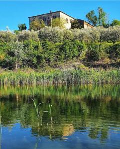 een gebouw op een heuvel naast een waterlichaam bij Agriturismo La Rugiada di Pociano in Monteroni dʼArbia