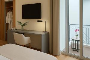 a bedroom with a desk with a tv and a window at Elite Patras Suites in Patra +17 photos