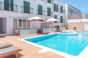 a swimming pool in front of a building at Hotel Jeni & Restaurant in Es Mercadal