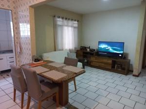 a living room with a table and a television at Caso 3 in São José