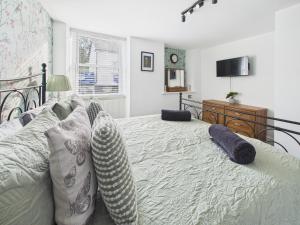 ein Schlafzimmer mit einem Bett mit Kissen und einem TV in der Unterkunft Spacious light and airy apartment with Cinema room in Ottery Saint Mary