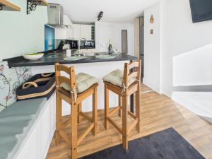 eine Küche mit zwei Stühlen und einer Theke in der Unterkunft Spacious light and airy apartment with Cinema room in Ottery Saint Mary