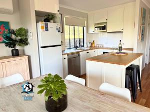 Lake & Reserve Front Bird Haven - 3BR في Encounter Bay: مطبخ مع طاولة وثلاجة بيضاء