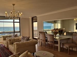 a living room with a table and chairs and the ocean at Bloubergstrand Beachfront Apartment Witsand 101 Tablemountain and ocean views in Cape Town