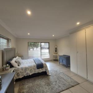 ein Schlafzimmer mit einem Bett und einem großen Fenster in der Unterkunft Luxurious 2-Bedroom French Cottage with parking in Roodepoort