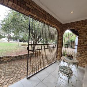 eine abgeschirmte Veranda mit einem Tisch und einem Stuhl in der Unterkunft Luxurious 2-Bedroom French Cottage with parking in Roodepoort + 12 Fotos