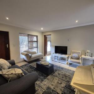 ein Wohnzimmer mit Sofa und Fernseher in der Unterkunft Luxurious 2-Bedroom French Cottage with parking in Roodepoort
