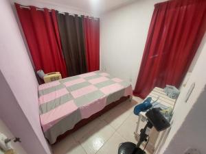 a small bedroom with a bed and red curtains at Casa de Arembepe in Camaçari +16 photos