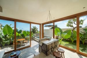a living room with large windows and a stone island at Mizu Homes By Avanterra in Nusa Lembongan