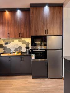 una cucina con elettrodomestici in acciaio inossidabile e mobili in legno di Jacob's Courts Apartment 6 a Kampala