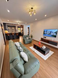 un soggiorno con divano verde e TV a schermo piatto di Jacob's Courts Apartment 6 a Kampala