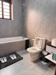 un bagno con WC, vasca e un paio di pantofole di Jacob's Courts Apartment 6 a Kampala