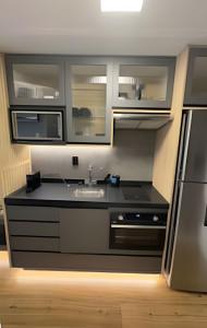 a kitchen with a black counter and a refrigerator at 602 - Estúdio elegante com piscina e academia in Sao Paulo