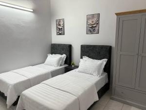 two beds with white sheets in a room at Wareesha Homestay, Corner Lot With Netflix in Padang Serai