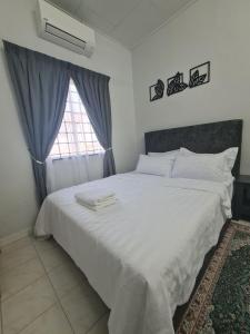 a bedroom with a large white bed with a window at Wareesha Homestay, Corner Lot With Netflix in Padang Serai