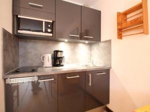 a kitchen with black cabinets and a sink and a microwave at Studio rénové à Flaine Forêt, résidence Sirius, à 500m des pistes – 5 couchages - FR-1-687-17 in Arâches-la-Frasse