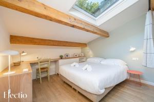 ペルテュイにあるLes Nids de la Diane - Appart'Confortsの大きな白いベッドと机のある寝室