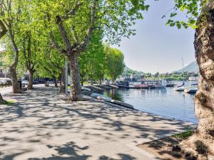 a sidewalk next to a river with trees and boats at Center House Via Anghileri in Lecco