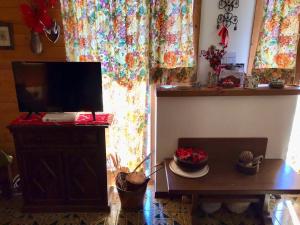 a living room with a tv and a table and curtains at Appartamento Dolomiti con parcheggio privato coperto in Folgarida
