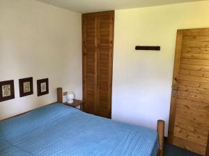a bedroom with a blue bed and a wooden door at Appartamento Dolomiti con parcheggio privato coperto in Folgarida